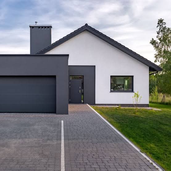 Maison contemporaine blanche et grise avec un garage attenant et une allée en pavés.